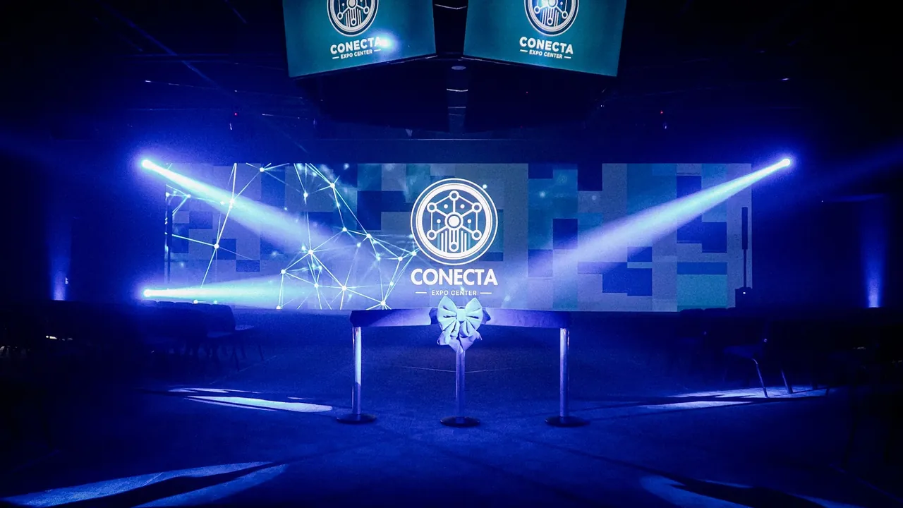 Palco do Auditório Principal montado para a inauguração, com a fita e o laço diante do painel de LED