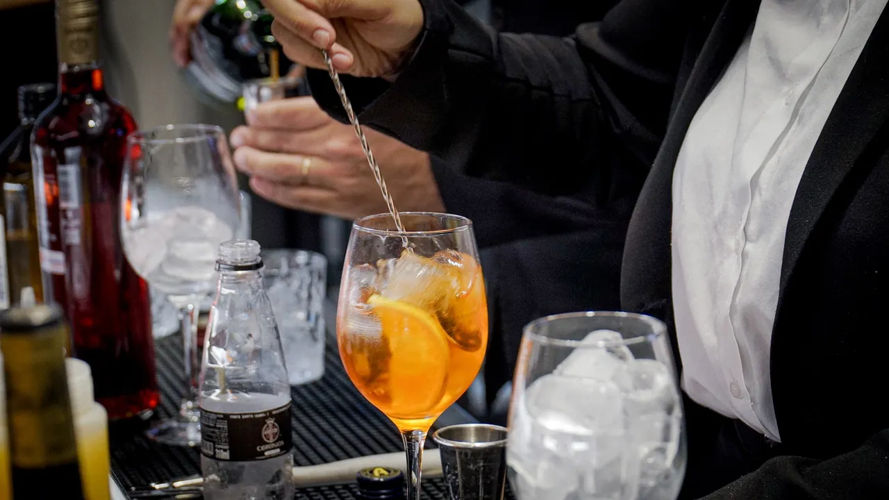 Drink com laranja sendo preparado no balcão do Coronata Wine Bar